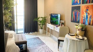 Una sala de estar moderna con un sofá, una mesa de comedor, un televisor y un ventanal con cortinas.