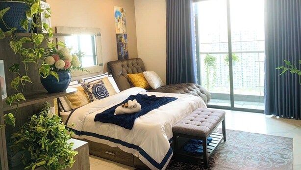 Un dormitorio moderno con una cama grande, un banco y vistas de la ciudad a través de amplias ventanas.