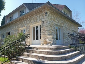 A stone house with a set of stone steps leading to a white door, surrounded by greenery. - Villa Beauregard Furnished Appartment La Roche Posay (la roche posay)