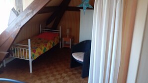 A small, cozy attic bedroom with a single bed, a chair, and a star decoration on the wall. - Villa Beauregard Furnished Appartment La Roche Posay (la roche posay)