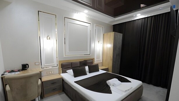 A modern hotel room with a large bed, a desk, and a chair. - Sharq Hotel (Urgench)