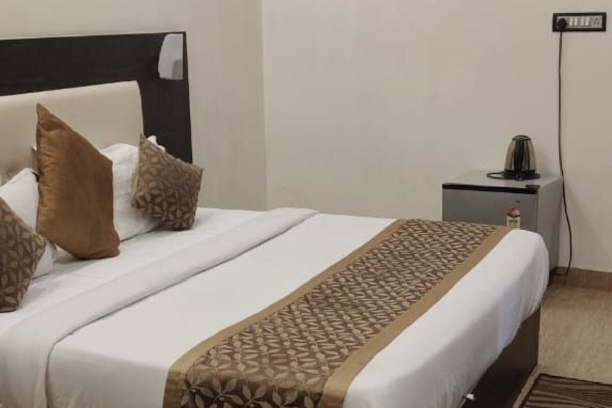A hotel room with a bed, a nightstand, a power outlet, and a ceiling fan.
