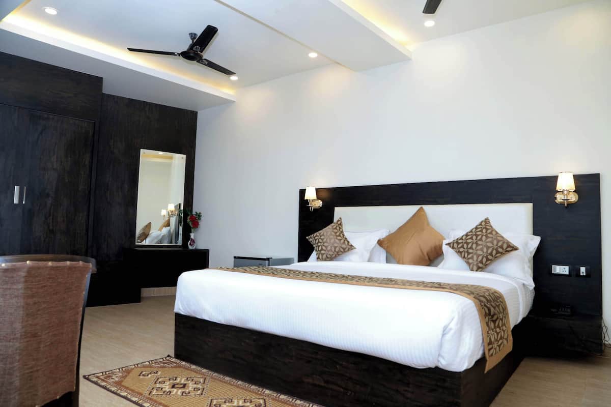 A modern hotel room with a large bed, dark wood headboard, and a ceiling fan.