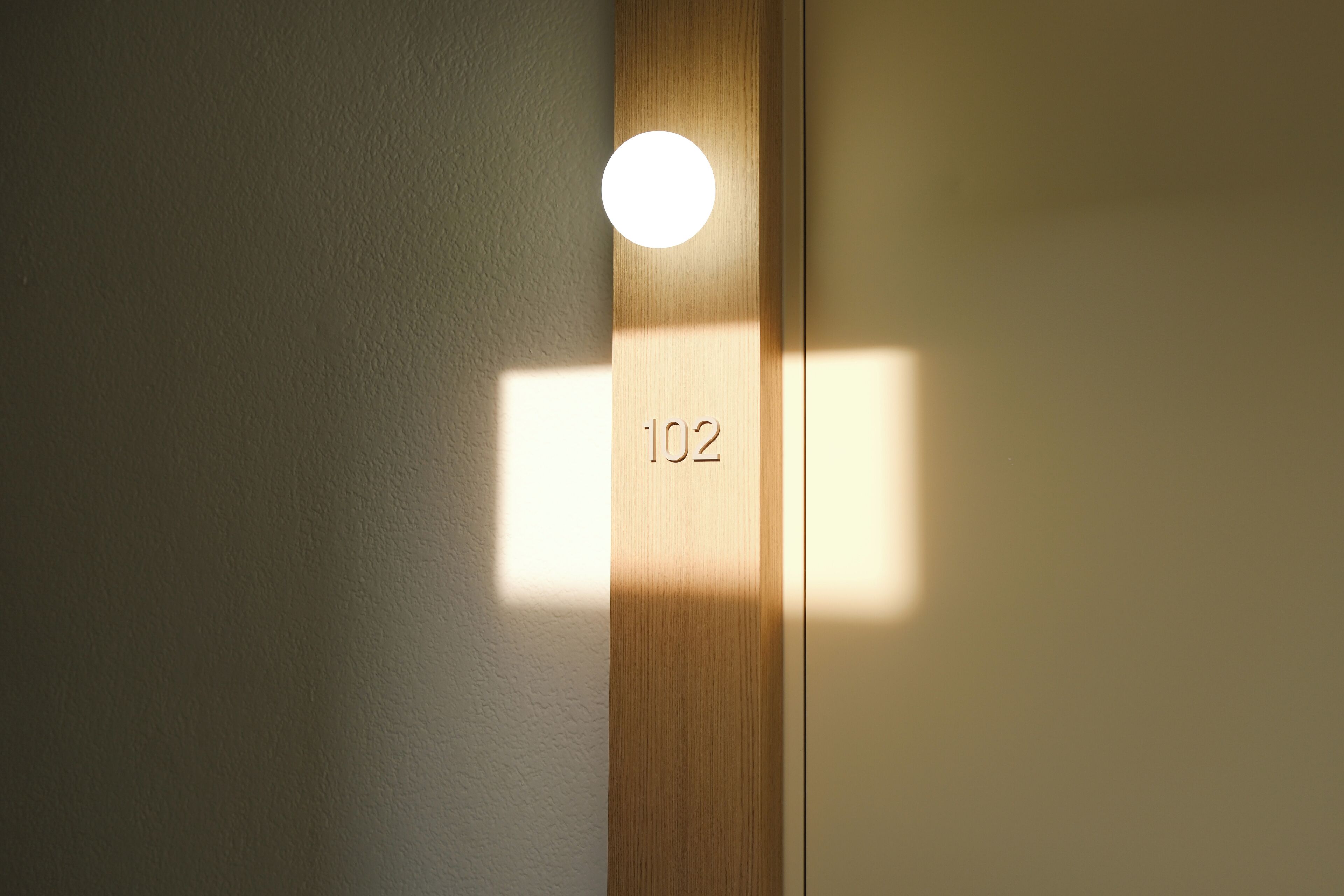 Een houten deur met een ronde lamp en het nummer 102.