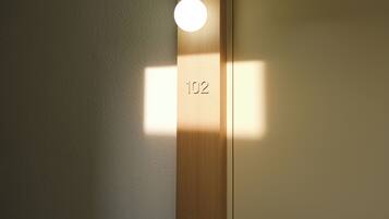 Een houten deur met een ronde lamp en het nummer 102.