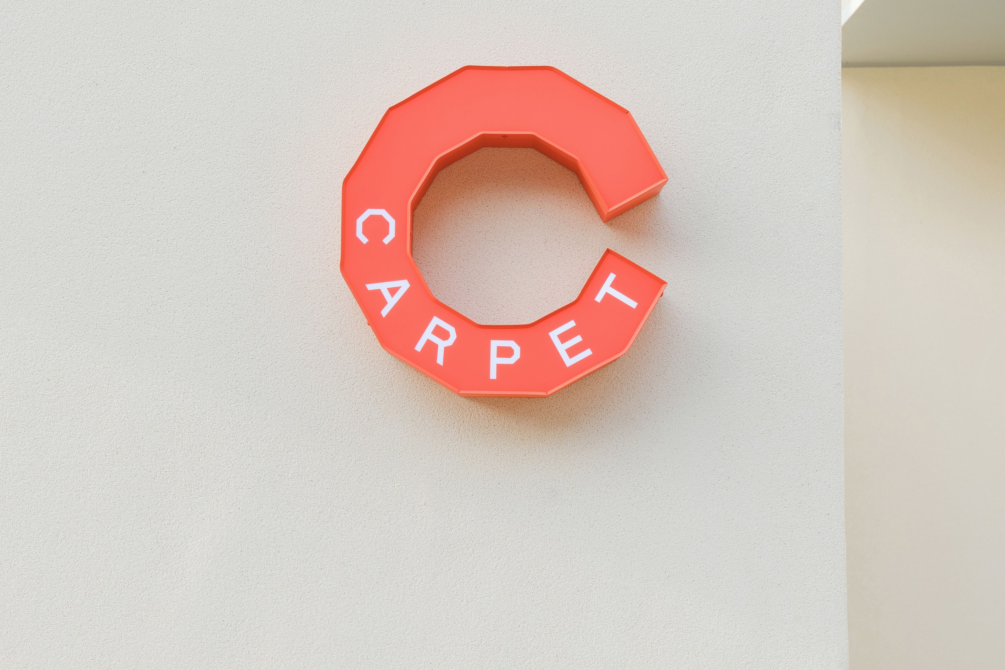 A red letter "C" with the word "CARPET" on a white wall.
