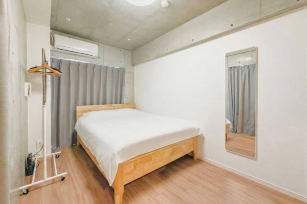 A bedroom with a single bed, a wardrobe, an air conditioning unit, and a mirror.