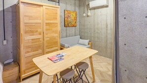 Una stanza con un tavolo in legno, due sedie, un divano, un ampio guardaroba e un quadro appeso al muro.