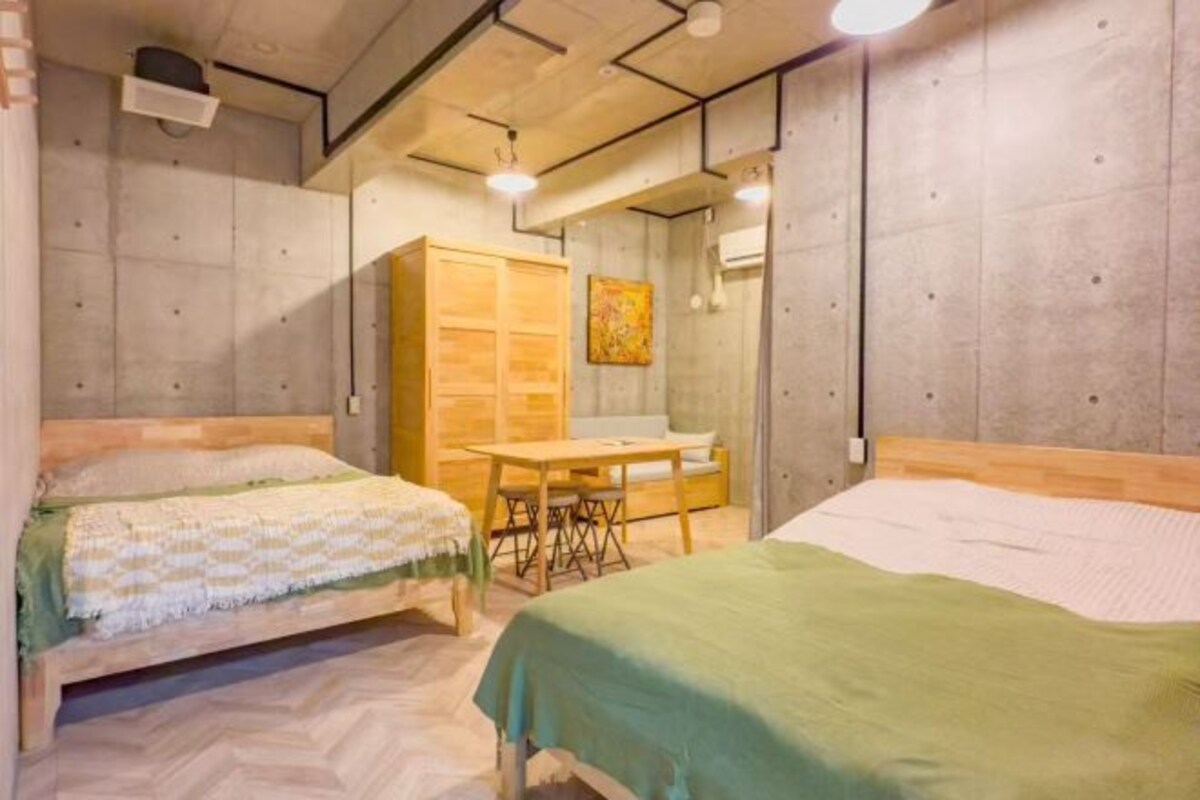A room with two beds, a wooden table, and a mirror.