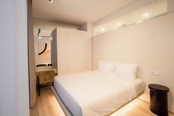 A modern bedroom with a bed, bedside table, and a desk area.