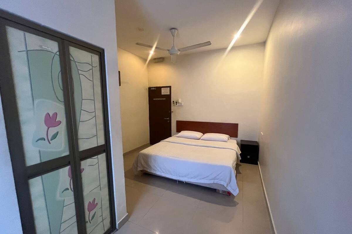 A bedroom with a bed, a ceiling fan, and a door.
