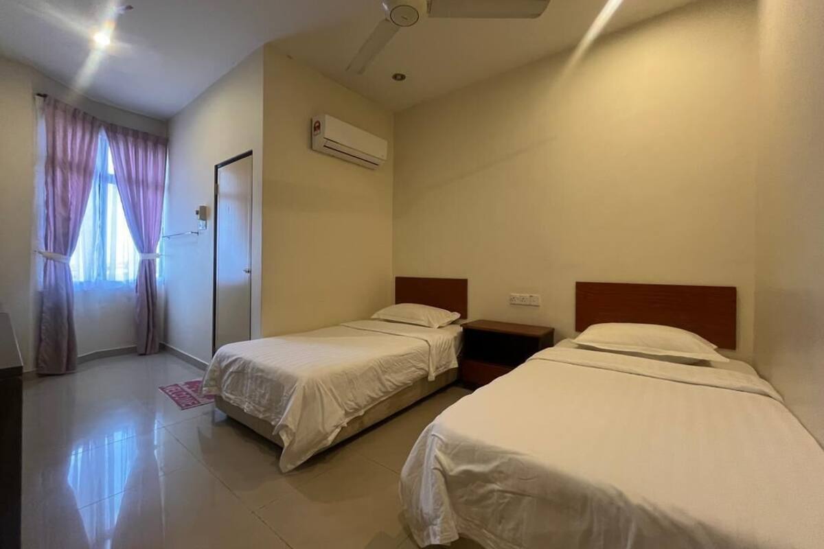 A hotel room with two single beds, a ceiling fan, an air conditioning unit, and a door leading to a balcony.