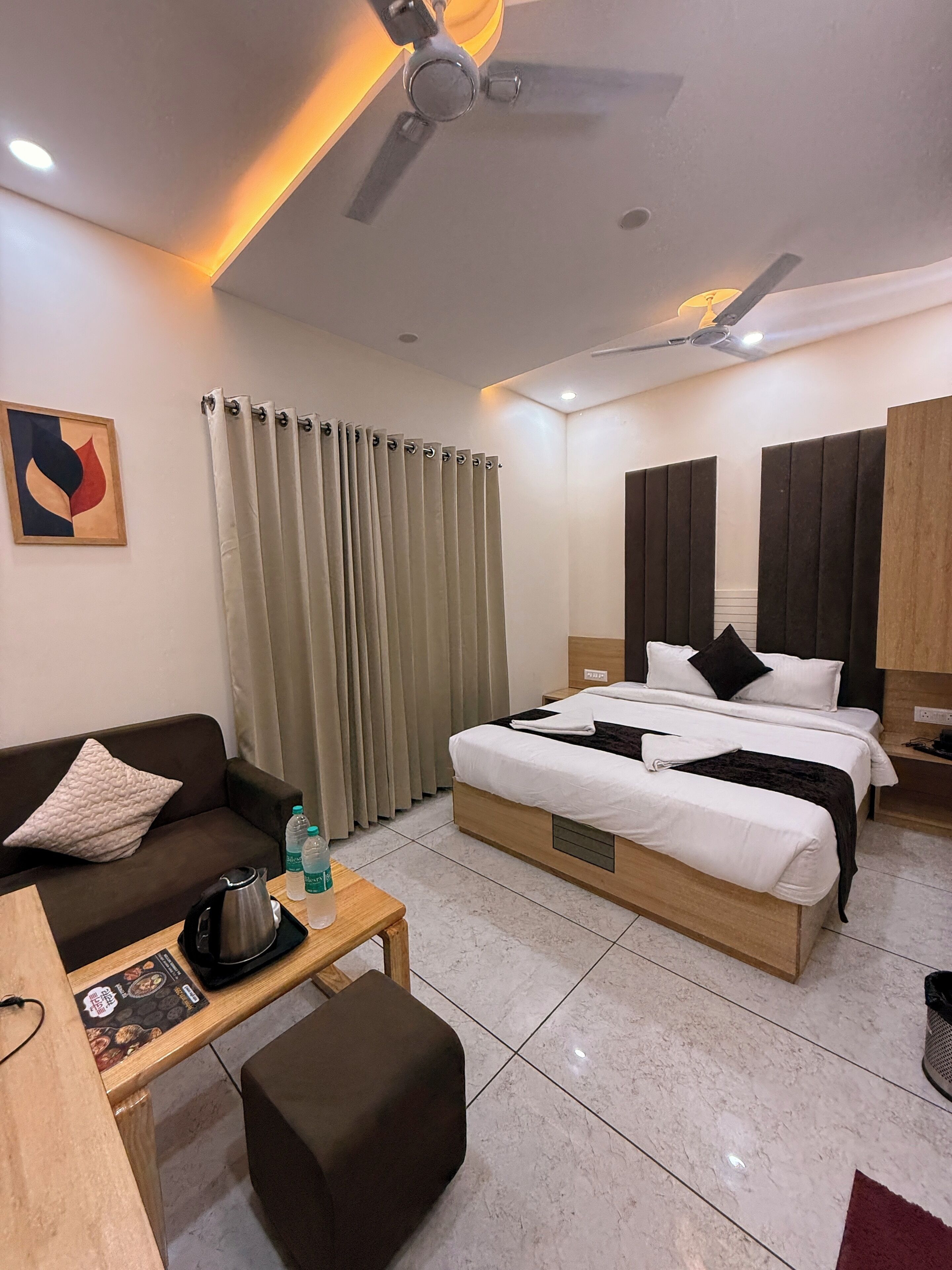 A hotel room with a bed, a sofa, a coffee table, and a ceiling fan.
