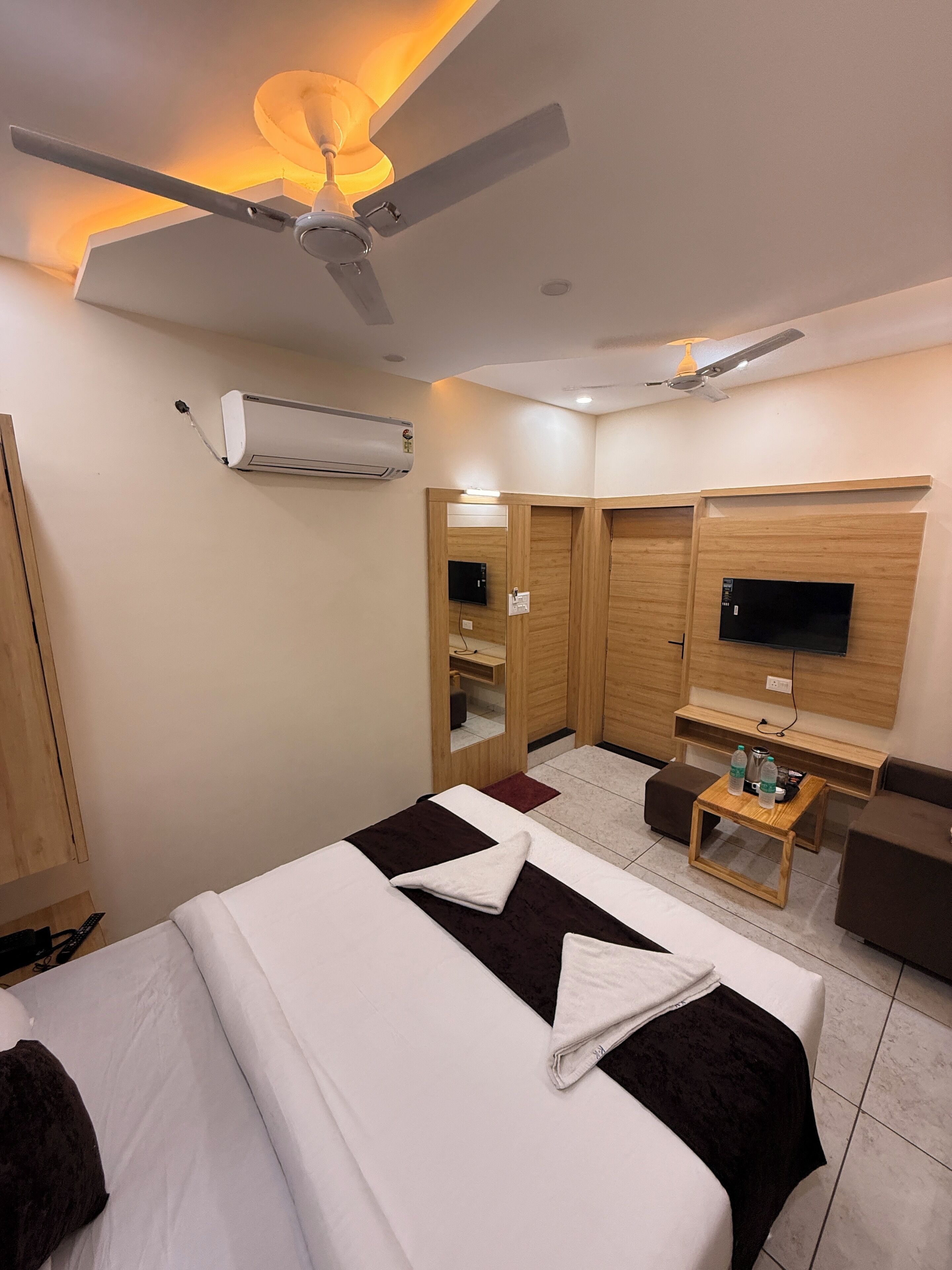 A hotel room with a bed, a TV, a desk, and a ceiling fan.