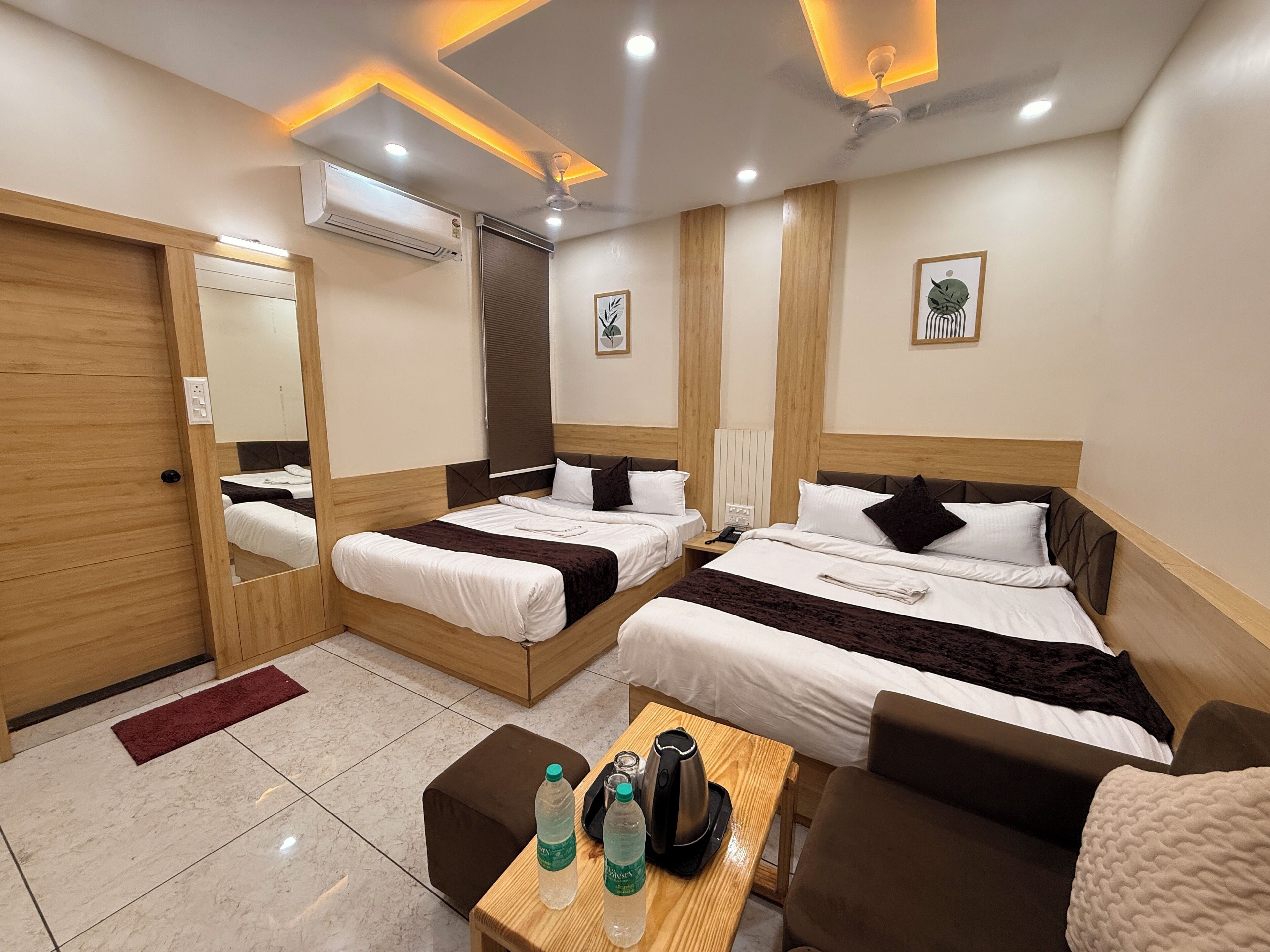 A hotel room with two beds, a wooden desk, a coffee maker, and a mirror.