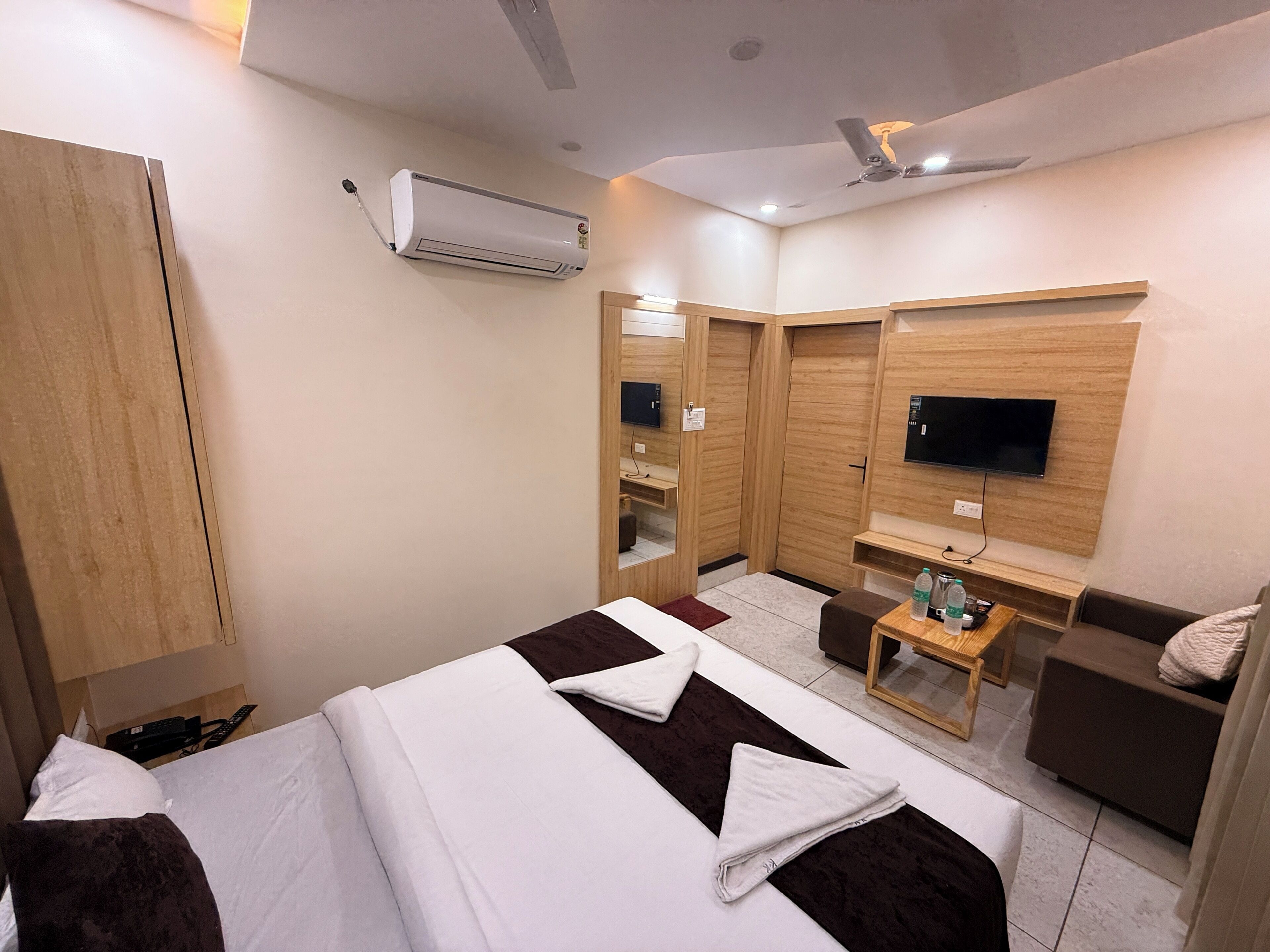 A hotel room with a bed, a desk, a TV, and a wardrobe.