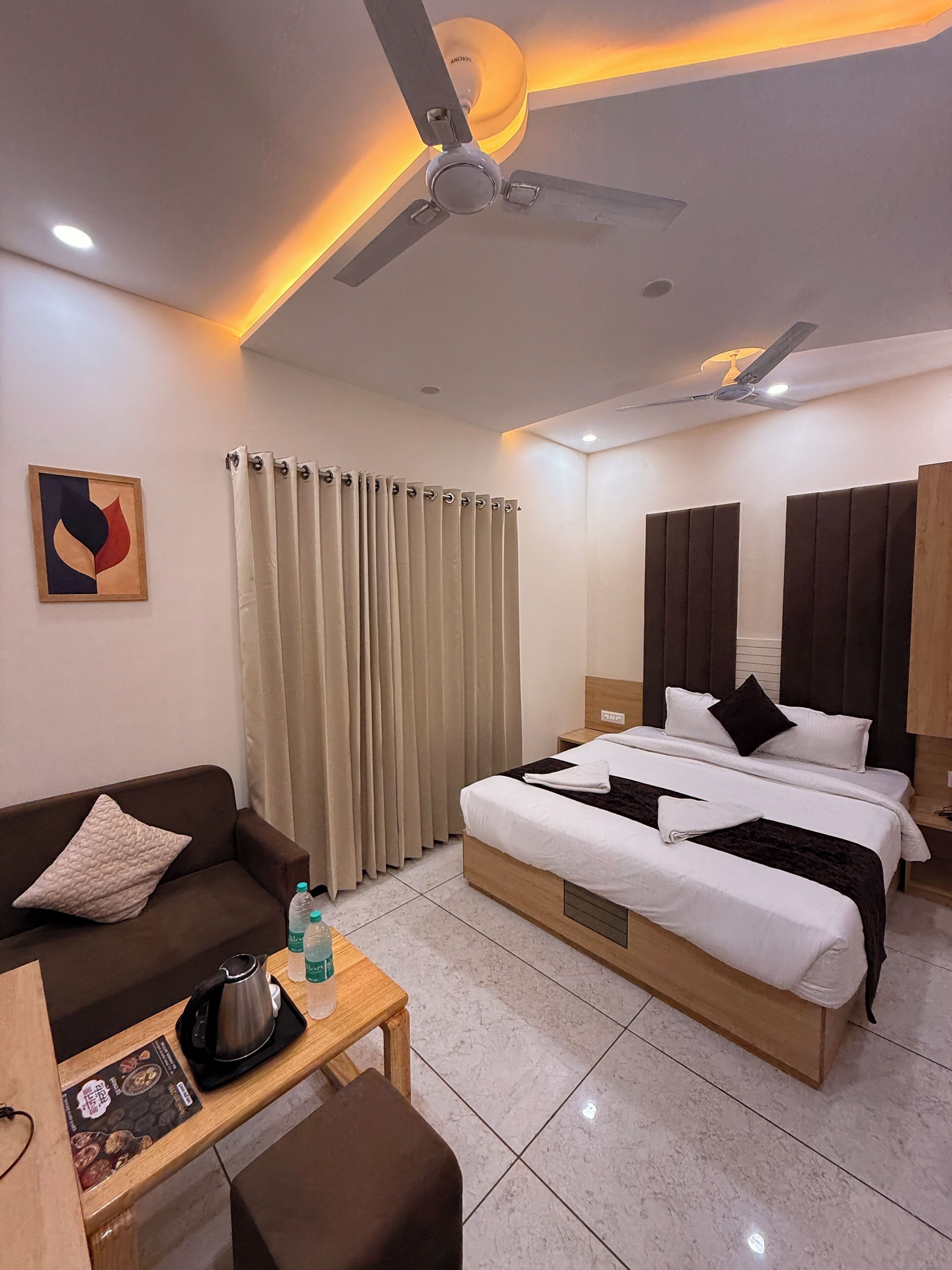 A hotel room with a bed, a sofa, a coffee table, and a ceiling fan.