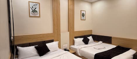 A hotel room with two beds, wooden headboards, white bedding, a dark brown throw blanket, a framed plant on the wall, and recessed ceiling lighting.