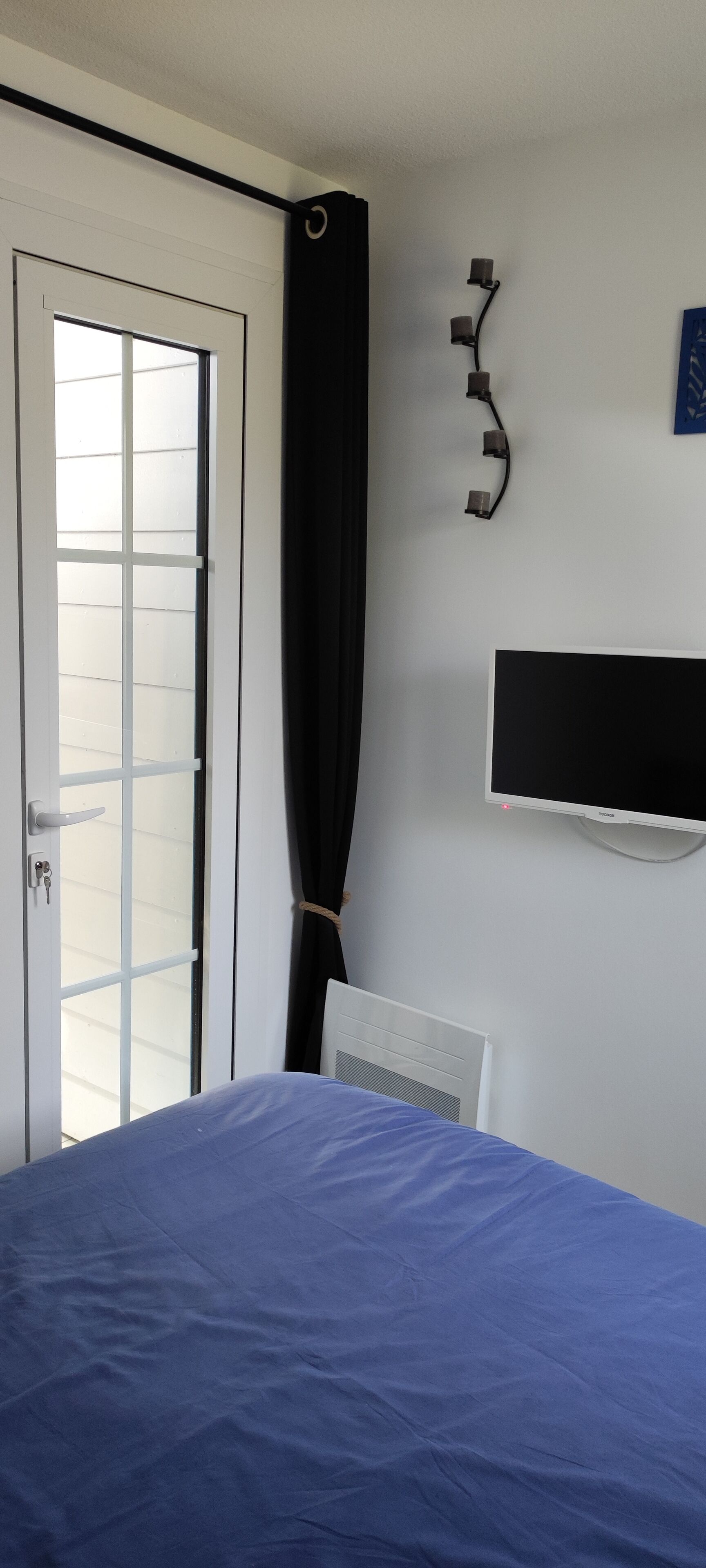A bedroom with a bed, a TV, a curtain, and a door.