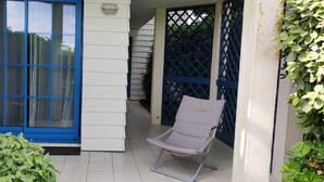 A covered outdoor area with a blue-framed window, a white wall, and a blue lattice gate. - Apartment -2 bedrooms, ground floor Port Bourgenay village with swimming pool access (Talmont-Saint-Hilaire)