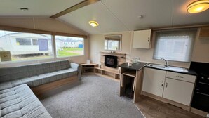 Une cuisine compacte pour camping-car, dotée d’une cuisinière intégrée, d’un évier et d’un coin salon avec un canapé.