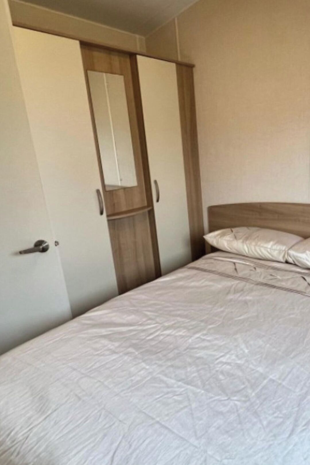 A bedroom with a bed, a wardrobe, and a mirror.
