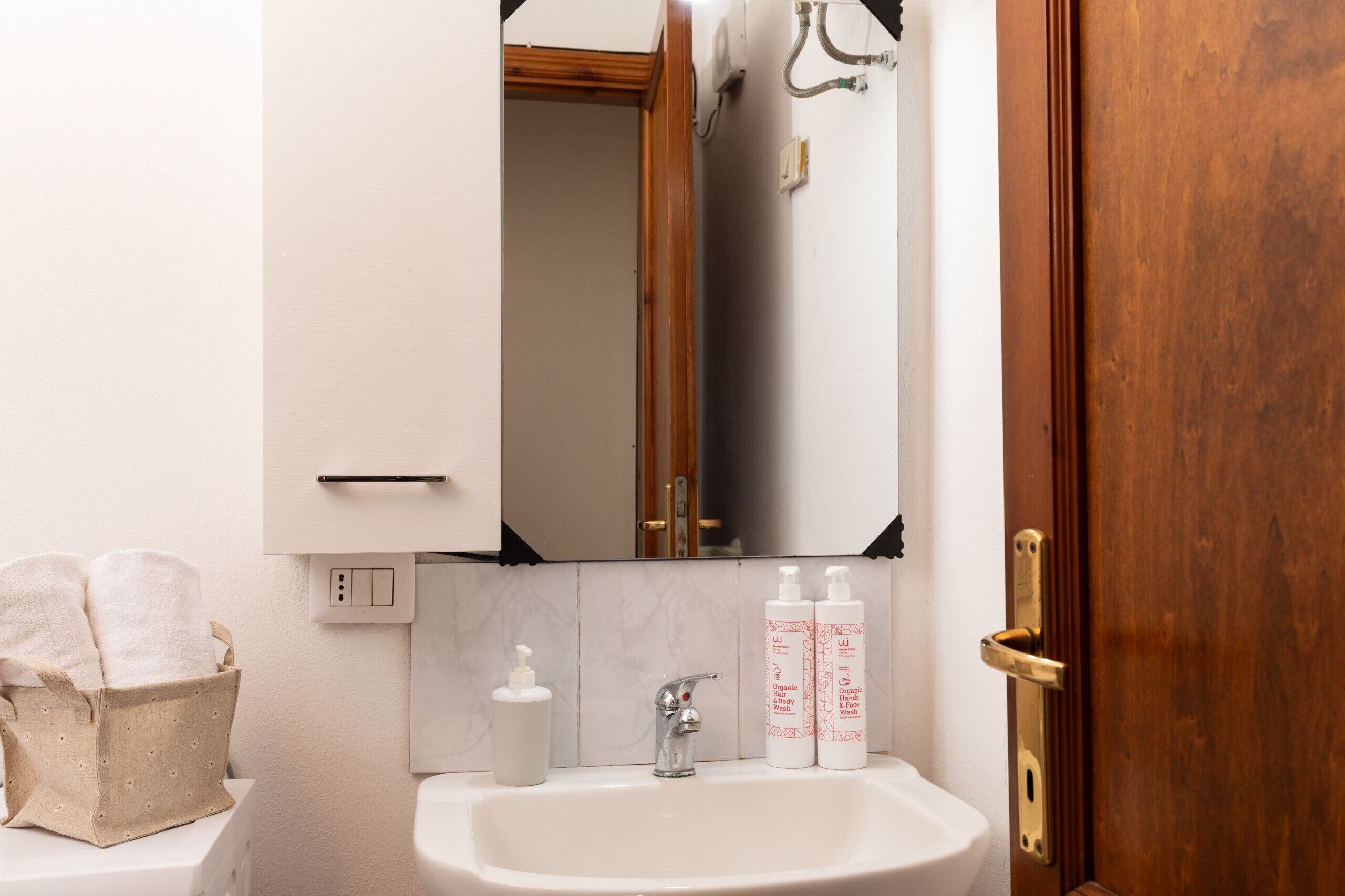 A bathroom with a white sink, a mirror, and two bottles of lotion.