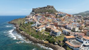 A coastal town with a prominent fort on a hill, colorful buildings, and a rocky shoreline.