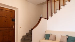 A wooden door, a staircase with a handrail, and a beige sofa with cushions.