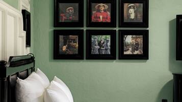 A room with two beds, a green wall, and six framed pictures.