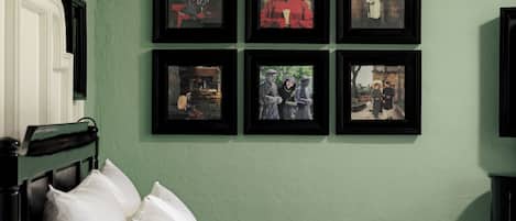A room with two beds, a green wall, and six framed pictures.