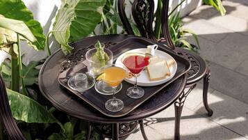 Une table sur laquelle se trouve un plateau contenant un sandwich, un verre de boisson rouge, un verre de jus d’orange et un petit pichet.