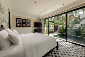 A bedroom with a large bed, a television, and a view of a swimming pool.