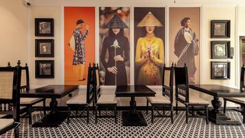 A room with a patterned floor, black tables, and chairs, and framed pictures on the walls.