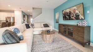 A modern living room with a sectional sofa, a wooden coffee table, and a large painting on the wall. - Spacious 8-bedroom apartment with WiFi, fitness room in wonderful Kissimmee (Kissimmee)