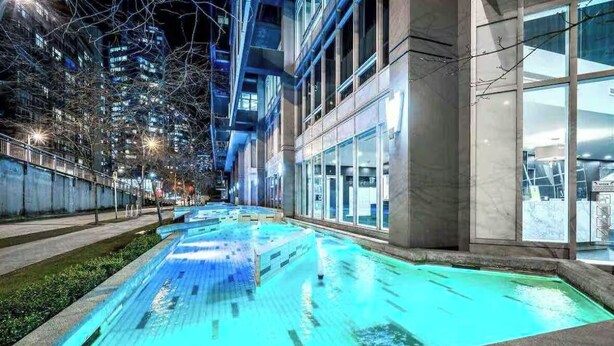 A swimming pool with clear water, surrounded by a building with large windows and a modern design. - Beautiful Downtown Condo- A/C, Parking, Laundry, Great Location! (Vancouver)
