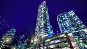 A high-rise building with multiple floors and balconies, surrounded by other modern buildings. - Beautiful Downtown Condo- A/C, Parking, Laundry, Great Location! (Vancouver)