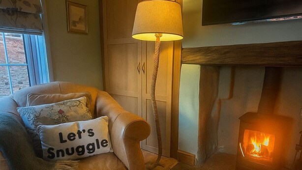 A cozy living room with a leather sofa, a fireplace, a television, and a lamp. - The Old Ropery at Mill Cottage - Unwind where ropes once twined (Ollerton)