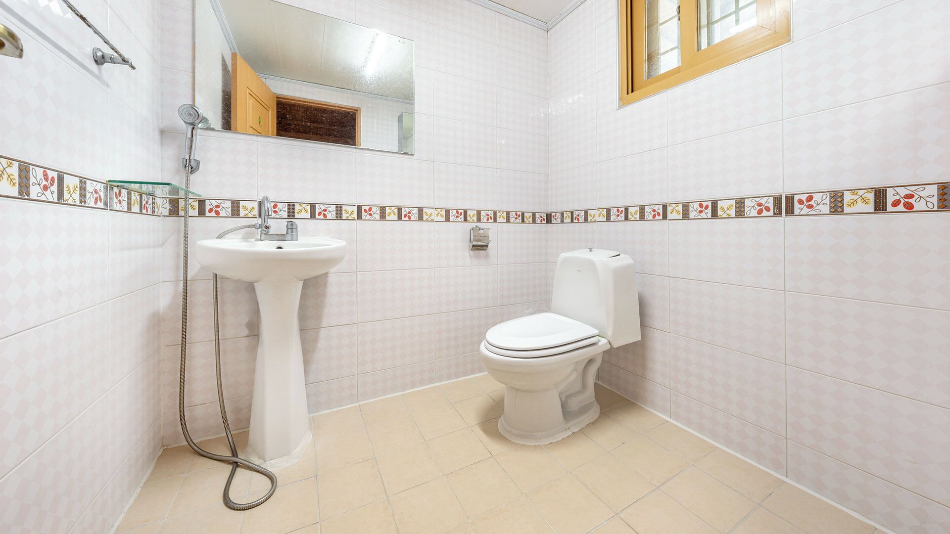 A bathroom with a pedestal sink, toilet, and a shower area.