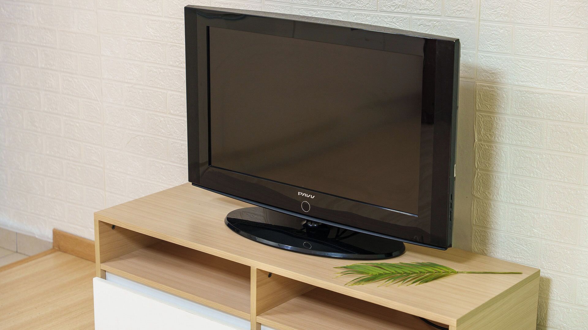 Un televisor de pantalla plana sobre un mueble de madera con un adorno de hoja.