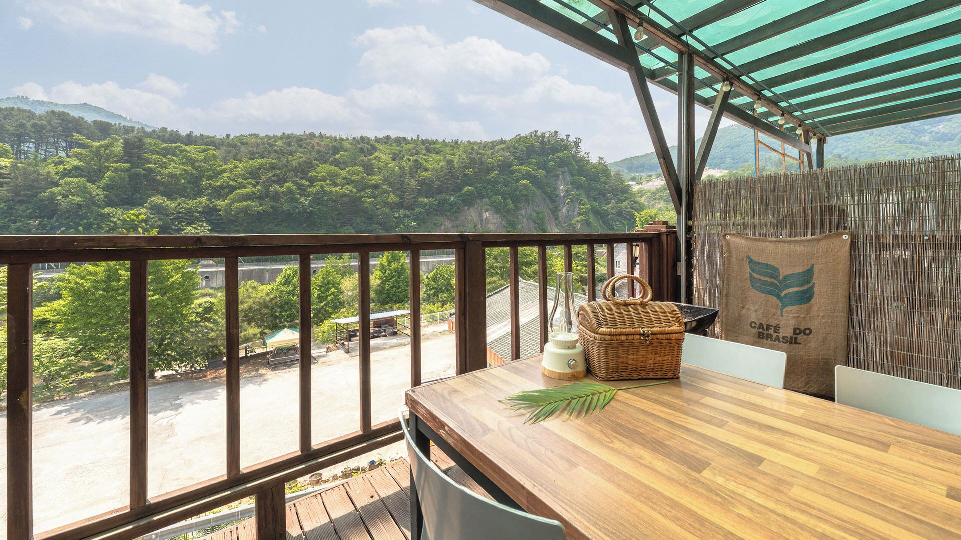 Eine Holzterrasse mit Blick auf eine üppige grüne Landschaft und einen Berg in der Ferne.