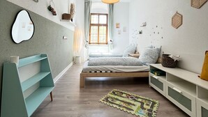 Un dormitorio moderno con una cama de madera, un banco verde azulado y un ventanal con cortinas.
