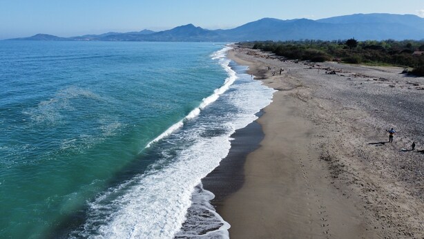 A beach with a clear view of the ocean and distant mountains.