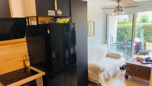A compact kitchen with a black refrigerator, a wooden countertop, and a built-in oven.