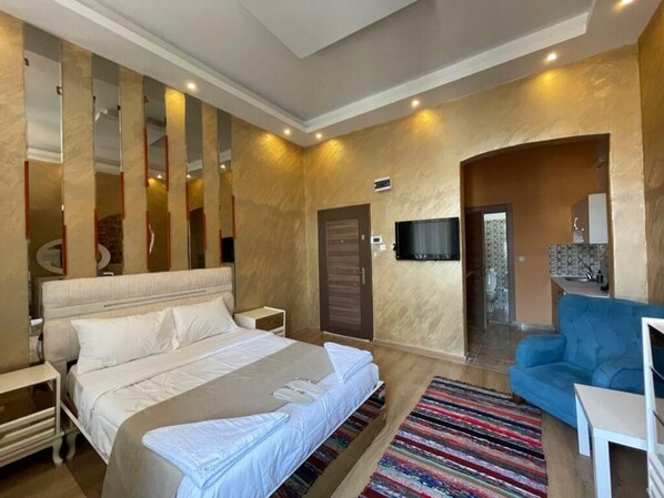 A bedroom with a large bed, a TV, a blue sofa, and a patterned rug. - Taksim Stone Wall Apartments (Istanbul)