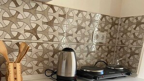 A kitchen with a patterned backsplash, a kettle, a toaster, and a drawer with utensils. - Taksim Stone Wall Apartments (Istanbul)