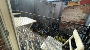 A balcony with a patterned floor, metal railing, and two white chairs. - Taksim Stone Wall Apartments (Istanbul)