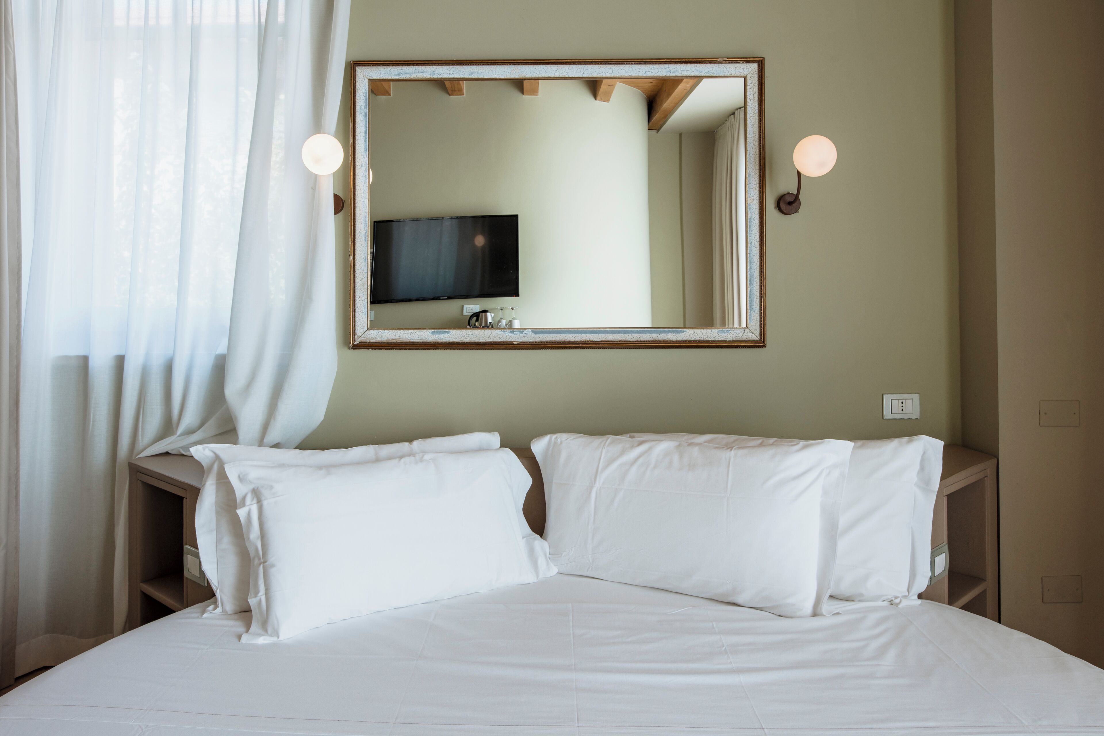 Ein Hotelzimmer mit einem Bett, einem Fernseher und einem Spiegel an der Wand.