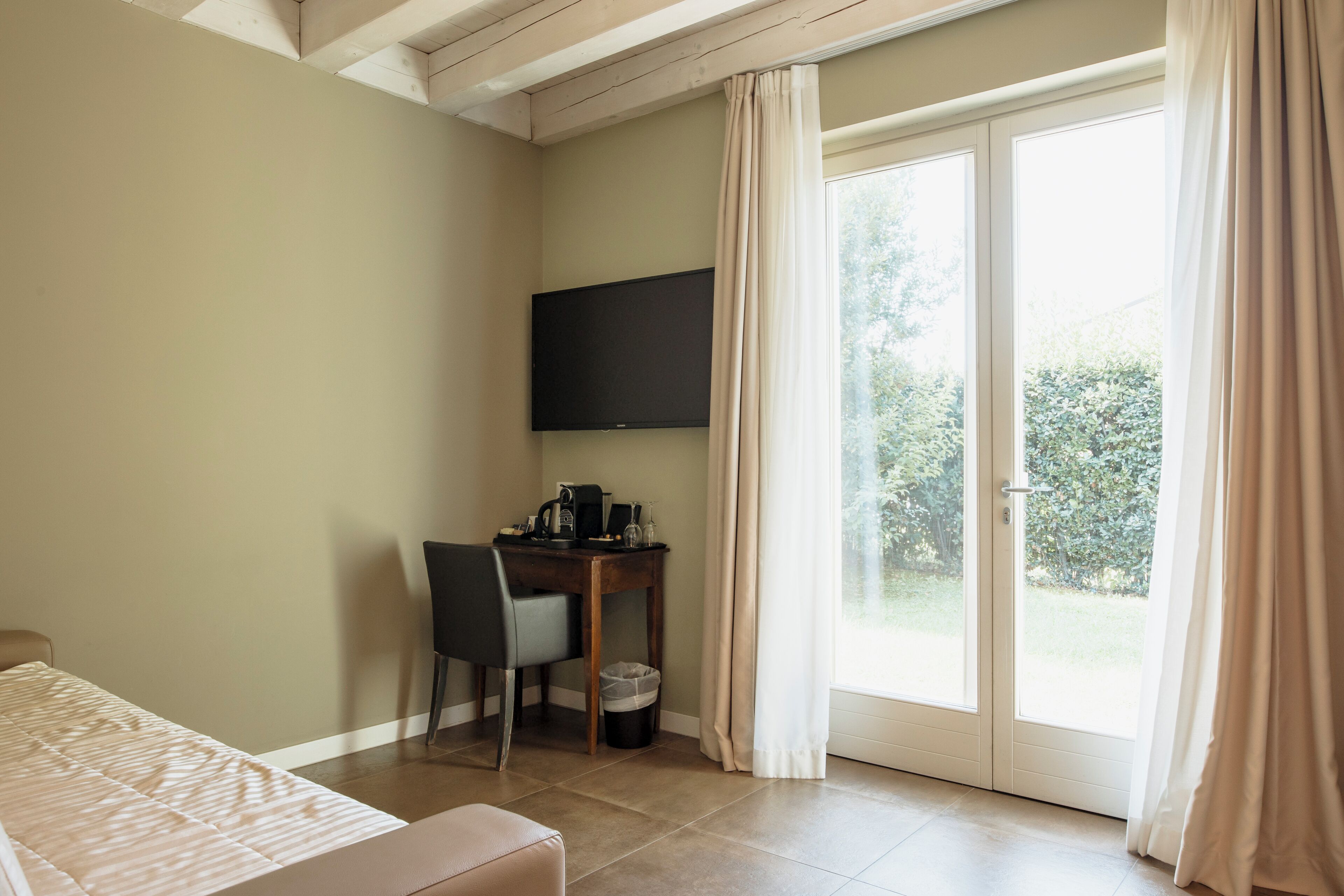 A room with a bed, a desk with a chair, a television, and a sliding glass door to the outdoors.