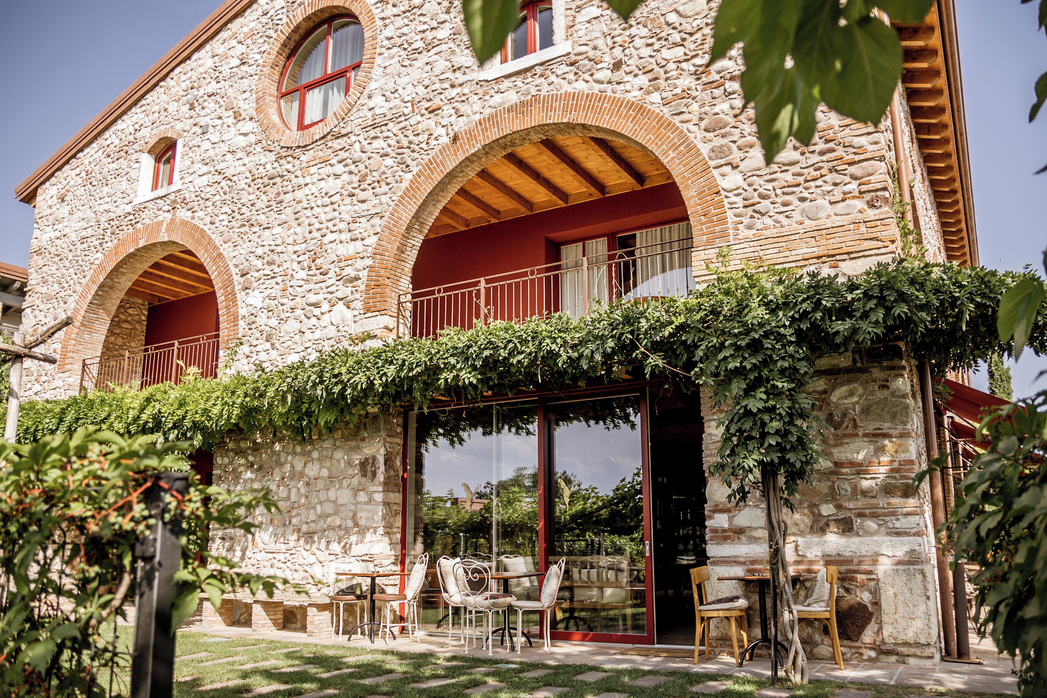 A stone building with arched windows and a balcony with chairs.